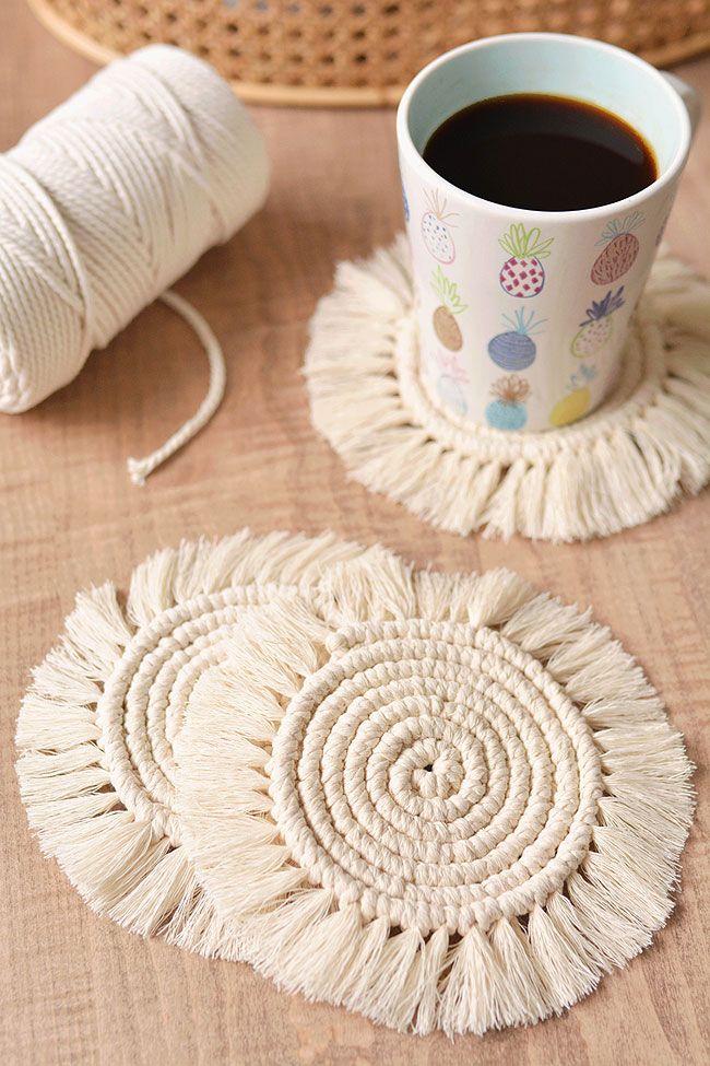 Handmade macrame coasters with coffee mug on wooden table, showcasing cozy, stylish home decor and craft materials.