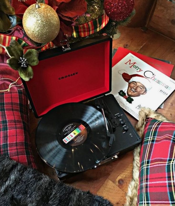 Vintage record player with Christmas vinyl, festive holiday décor, plaid pillows, and ornaments. Warm holiday atmosphere.