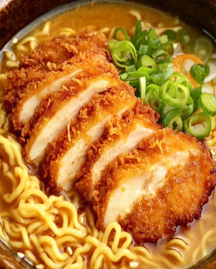 Close-up of katsu ramen noodles topped with crispy breaded pork and fresh green onions, served in a rich broth.