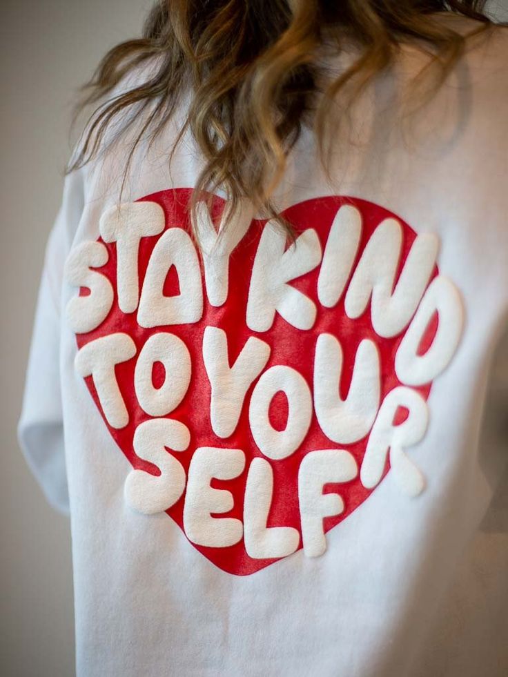 White shirt with a red heart design and Stay Kind to Yourself message on the back. Perfect for self-care reminders.