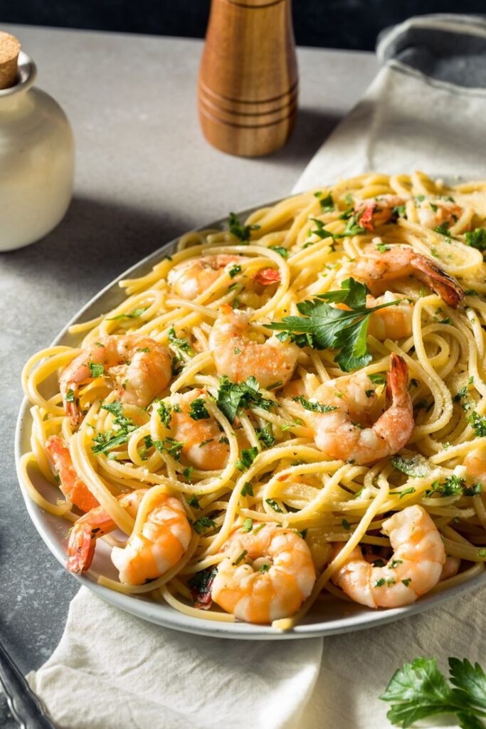 Delicious shrimp pasta with garlic and parsley on a plate, garnished with fresh herbs, ready to serve.