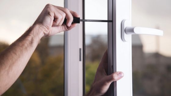 Person fixing a window handle with a screwdriver, highlighting DIY home repair and maintenance.