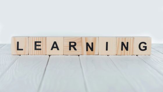 Wooden blocks spelling Learning on a light wooden surface, symbolizing education and growth.