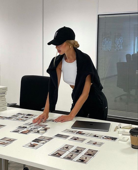 Woman organizing photo prints on a table in a modern office setting.