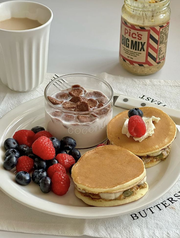 Breakfast plate with pancakes, fresh berries, yogurt, and coffee for a delicious morning meal.