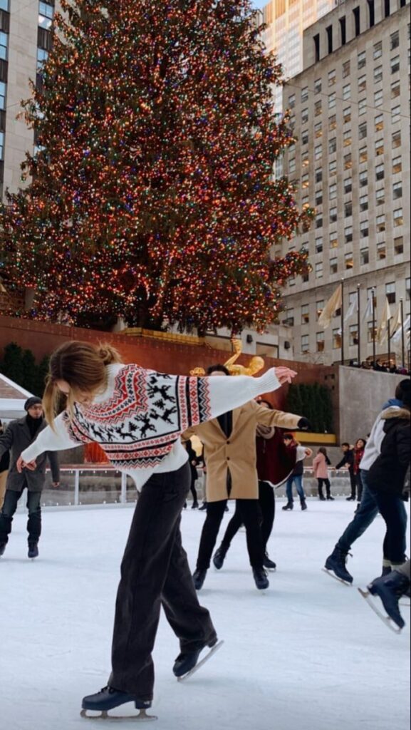 Ice skaters gracefully glide at Rockefeller Center rink beneath a dazzling Christmas tree.