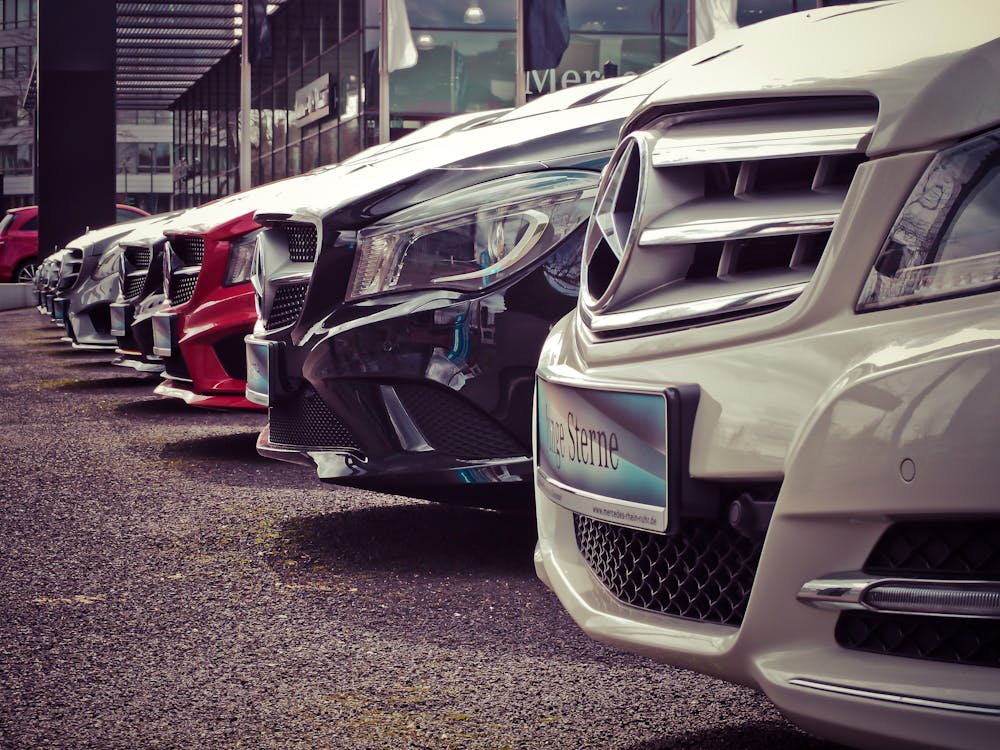 Row of luxury cars parked outside a dealership, showcasing various sleek models and elegant designs.