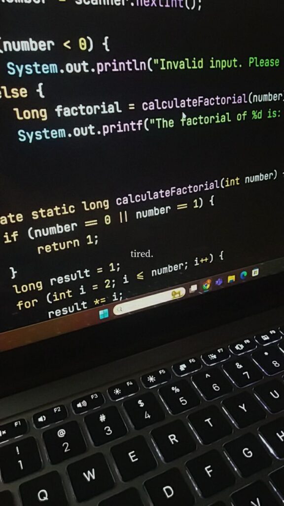 Computer screen displaying Java code for calculating factorial with a keyboard in view. Code optimization concept.