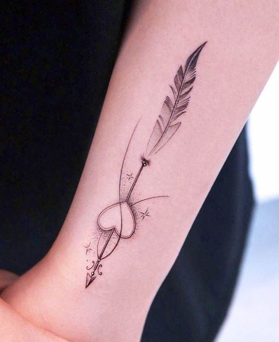 Minimalist heart and arrow tattoo on forearm, featuring delicate lines and dotwork.