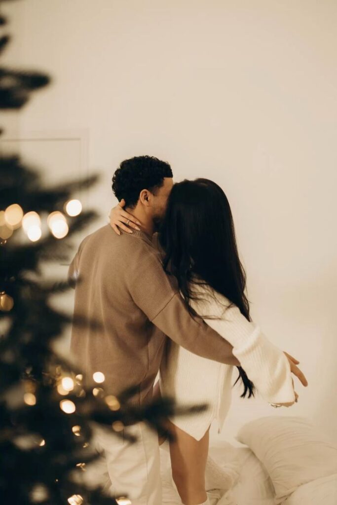 Новогодняя лавстори Couple embracing near a Christmas tree, creating a cozy holiday atmosphere. | Sky Rye Design Couple embracing near a Christmas tree, creating a cozy holiday atmosphere.