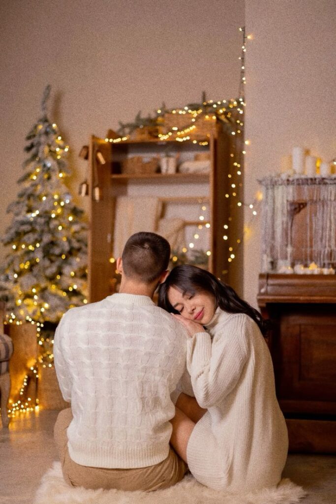 фотосессия пара лавстори новогодняя Cozy couple in white sweaters enjoying a festive holiday setting with lights and a decorated tree. | Sky Rye Design Cozy couple in white sweaters enjoying a festive holiday setting with lights and a decorated tree.