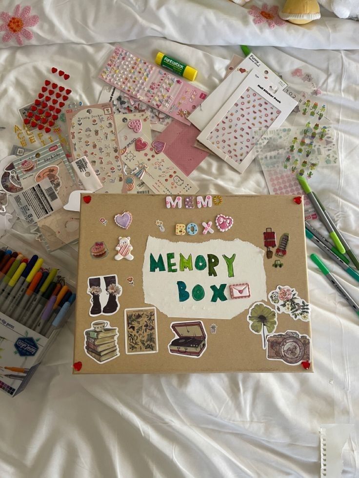 Creative memory box with stickers and markers on a bedspread, perfect for scrapbook and DIY enthusiasts.