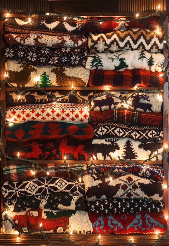 Cozy stacked festive sweaters adorned with twinkling lights, featuring winter-themed patterns and classic holiday designs.