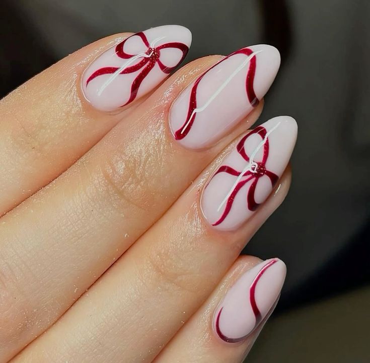 Elegant manicure with pink nails and red ribbon designs, perfect for festive occasions.