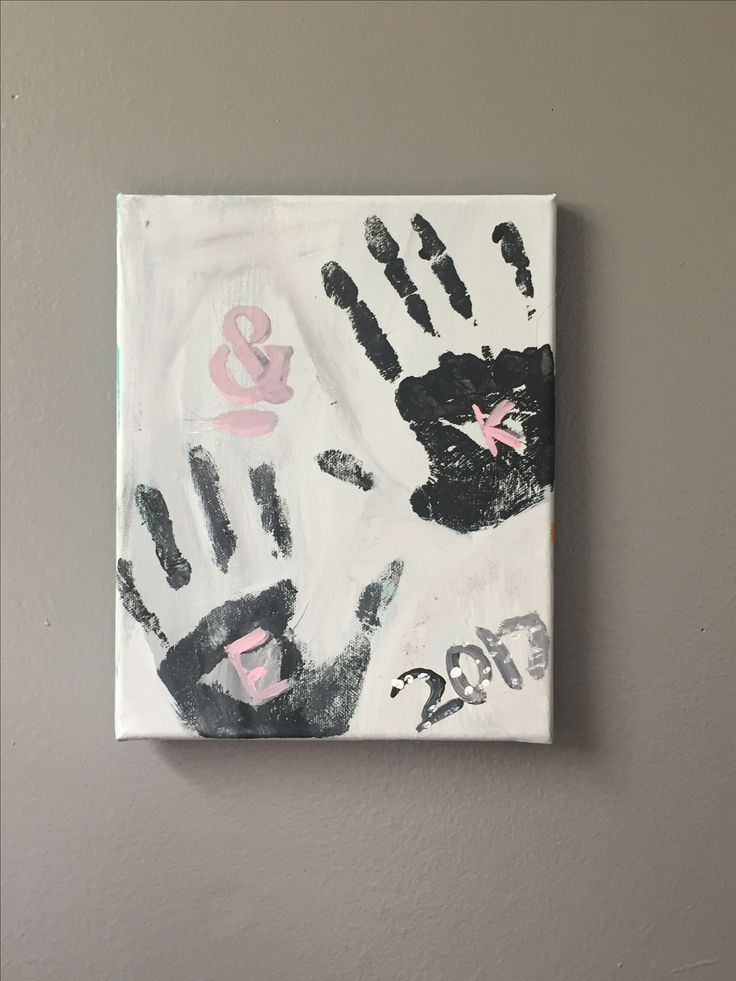 Canvas with two black handprints, pink initials E & K, and the year 2017 on a gray background.