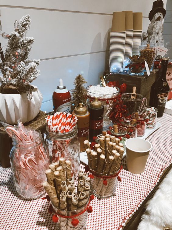 Festive hot chocolate bar setup with candy canes, toppings, and holiday decorations on a cozy table.