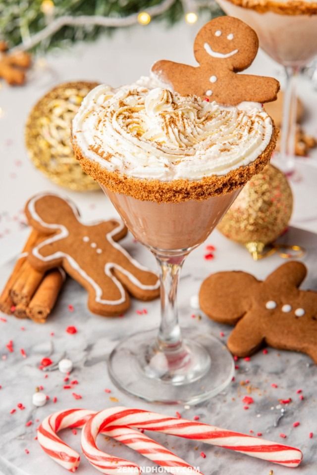 Festive gingerbread martini with whipped cream and gingerbread cookies, surrounded by candy canes and holiday decor.