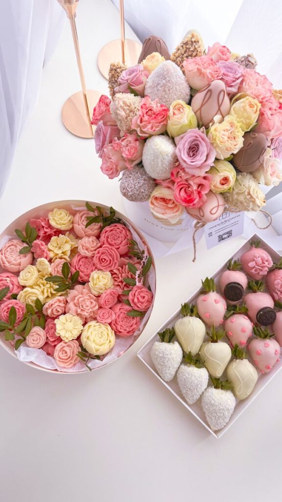 Bouquet of pink roses with chocolate-dipped strawberries and floral cupcakes, perfect for a romantic celebration.