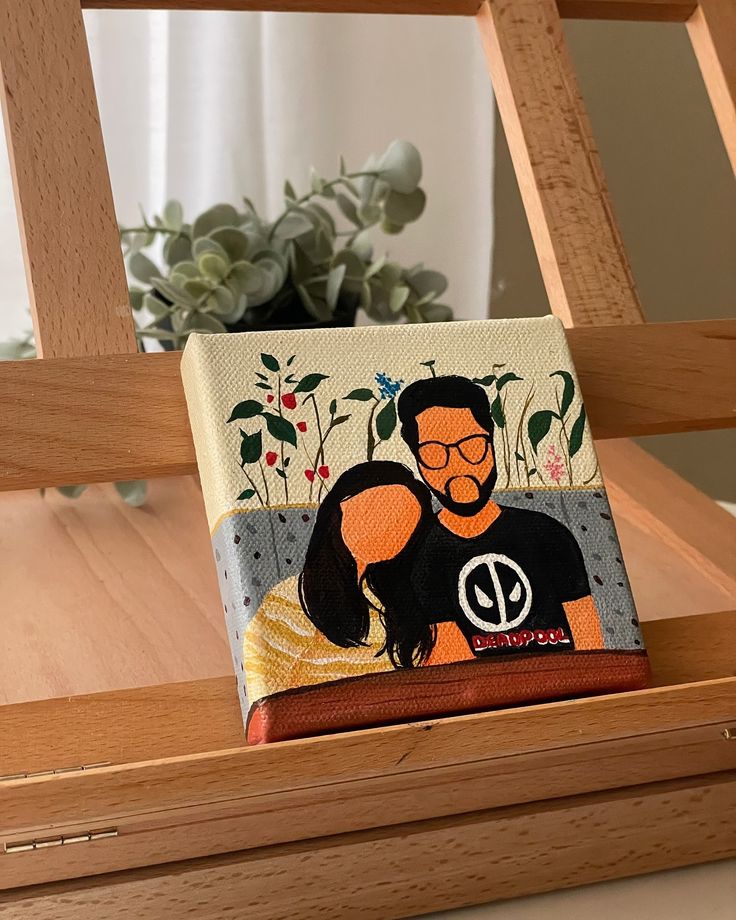 Illustrative painting of a couple on canvas, displayed on a wooden easel with plants in the background.