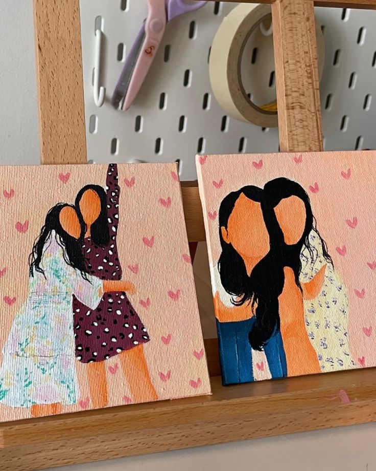 Colorful minimalist paintings of two couples embracing on canvas with heart patterns, displayed on a wooden easel.