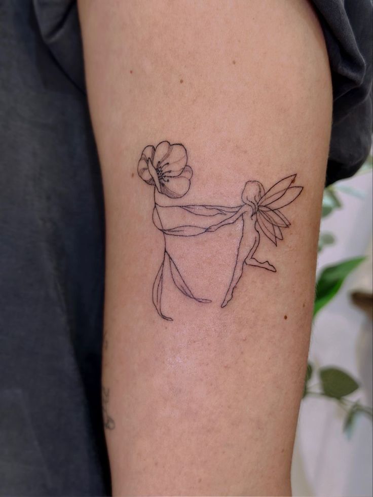 Minimalist tattoo of a fairy holding a flower, elegantly inked on an arm.