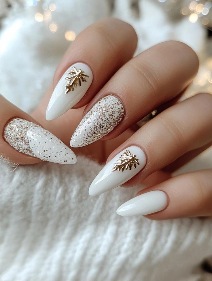 Elegant white nails with gold glitter and leaf accents, perfect for a festive or winter-themed look.