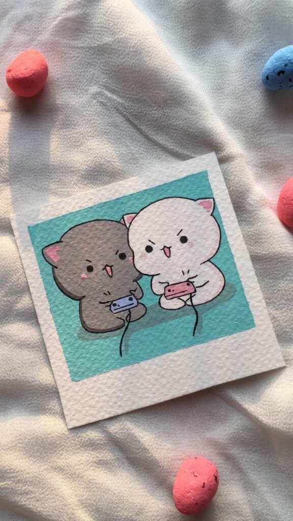 Cute cartoon cats playing video games on a card, surrounded by colored stones on fabric.