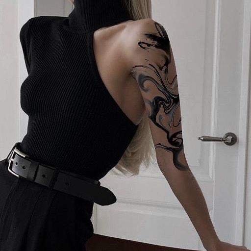 Fashionable person in a black one-shoulder top showcasing a unique black and white arm tattoo.