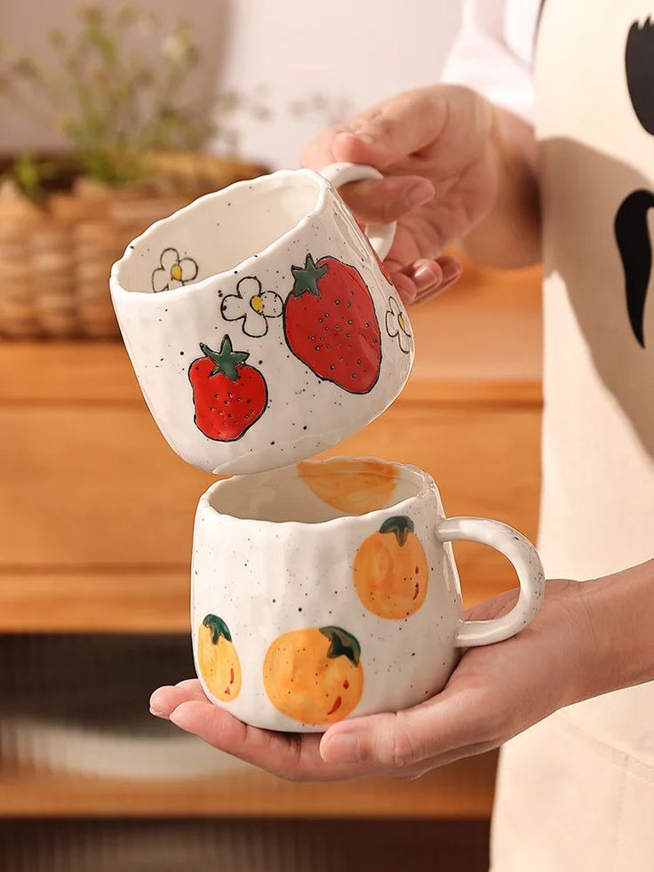 Ceramic mugs with hand-painted fruit designs, perfect for kitchen decor and coffee lovers.