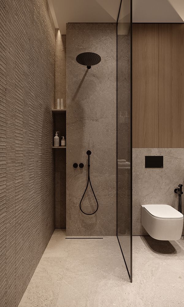 Minimalist bathroom with glass shower partition and modern fixtures, featuring beige stone walls and flooring.