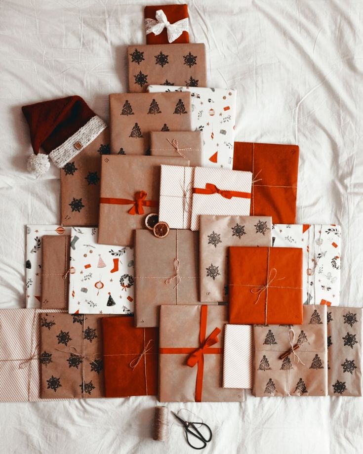 Christmas gifts arranged in a tree shape with festive wrapping paper and Santa hat on white background.