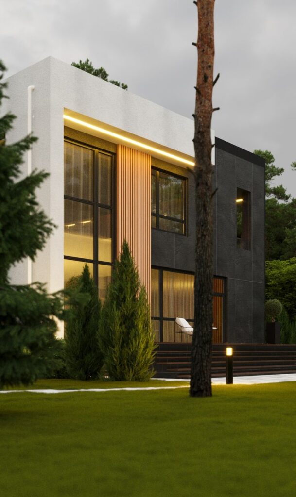 Modern minimalist home exterior with large windows and surrounding greenery at dusk.