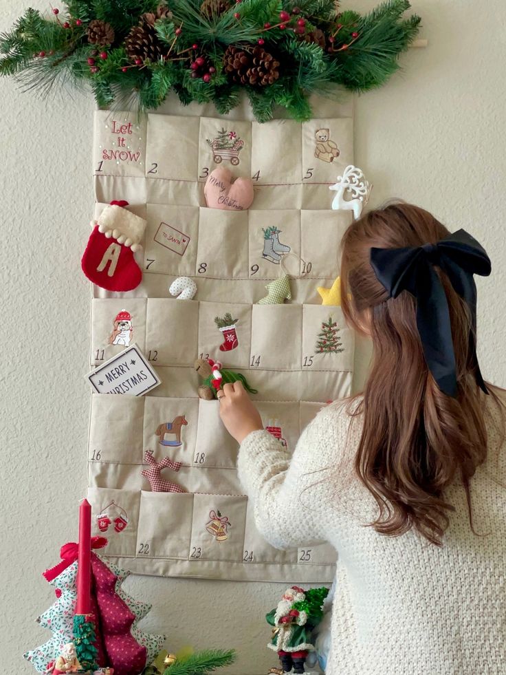 Girl interacting with a Christmas advent calendar, featuring festive decorations and a pinecone garland.