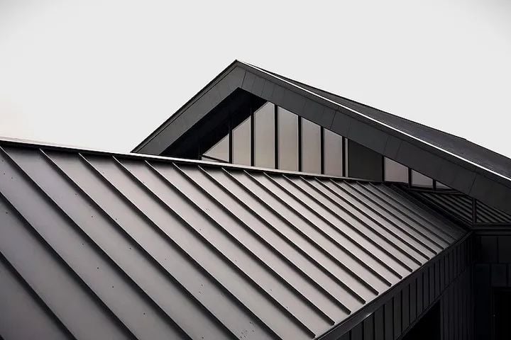 Commercial Roof 1 Diagonal standing-seam metal roof panels on a modern gray building with triangular gabled windows | Sky Rye Design Diagonal standing-seam metal roof panels on a modern gray building with triangular gabled windows