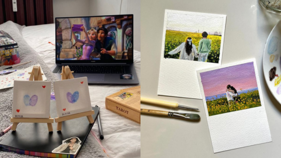 Painting and digital art setup with movie on laptop; includes mini canvases and wedding-themed artwork on paper.