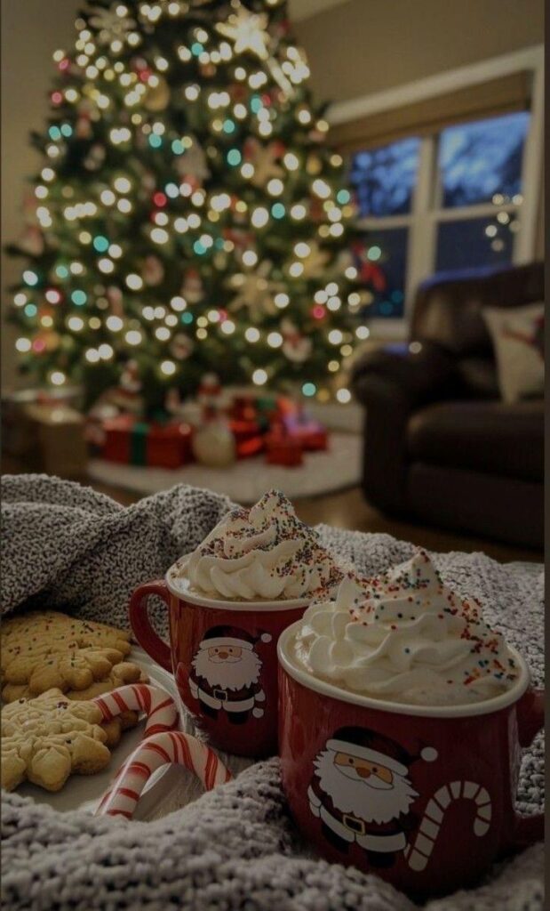 Cozy holiday scene with hot cocoa mugs, cookies, and candy canes in front of a decorated Christmas tree.