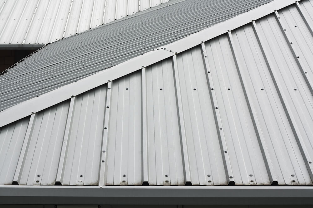 Close-up of a modern metal roof with overlapping panels and visible fasteners, showcasing durable construction.