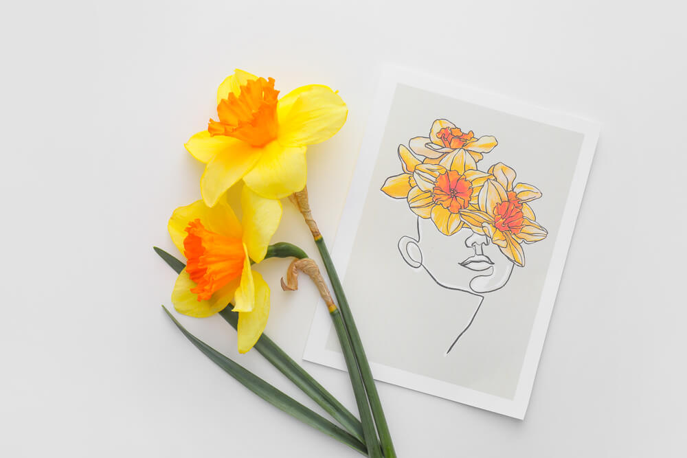 Yellow daffodils next to a minimalist art print depicting a face with floral design.