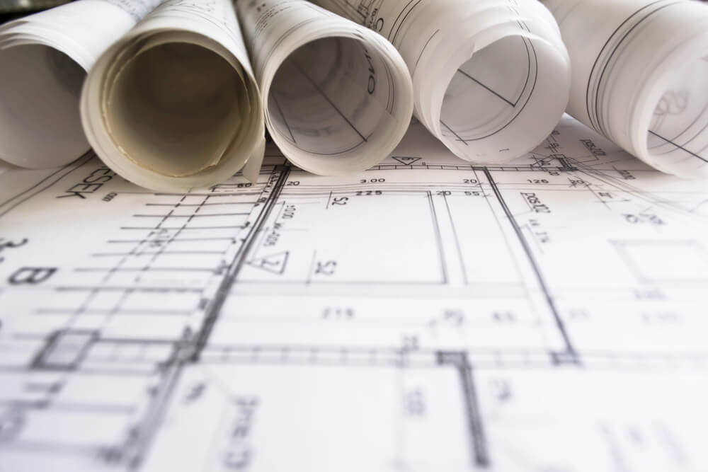 Architectural blueprints and rolled plans on a table, showcasing detailed building designs and technical drawings.