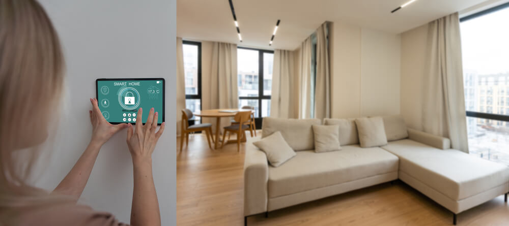 Woman using smart home tablet in modern living room with large windows and beige sofa.