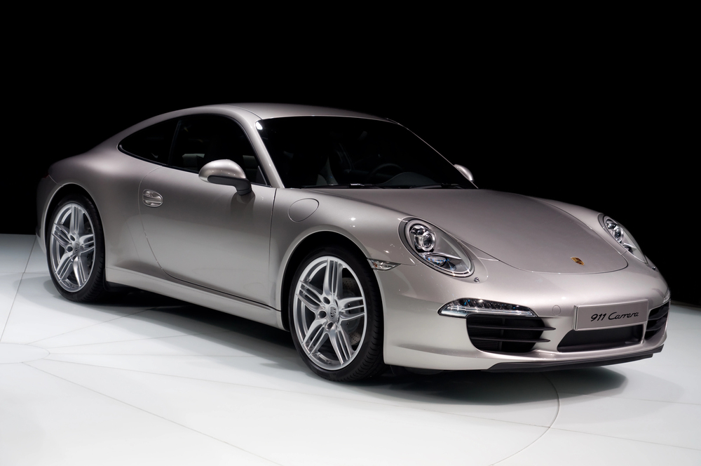 Silver sports car on black background, showcasing sleek design and shiny rims.