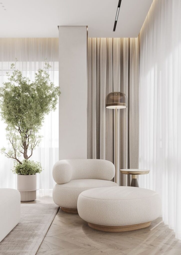 Modern living room with white armchair, ottoman, floor lamp, and indoor plant near sheer curtains. Scandinavian decor.