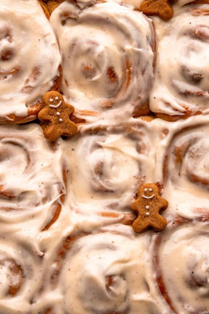 Frosted cinnamon rolls with gingerbread cookies, perfect for a festive treat.