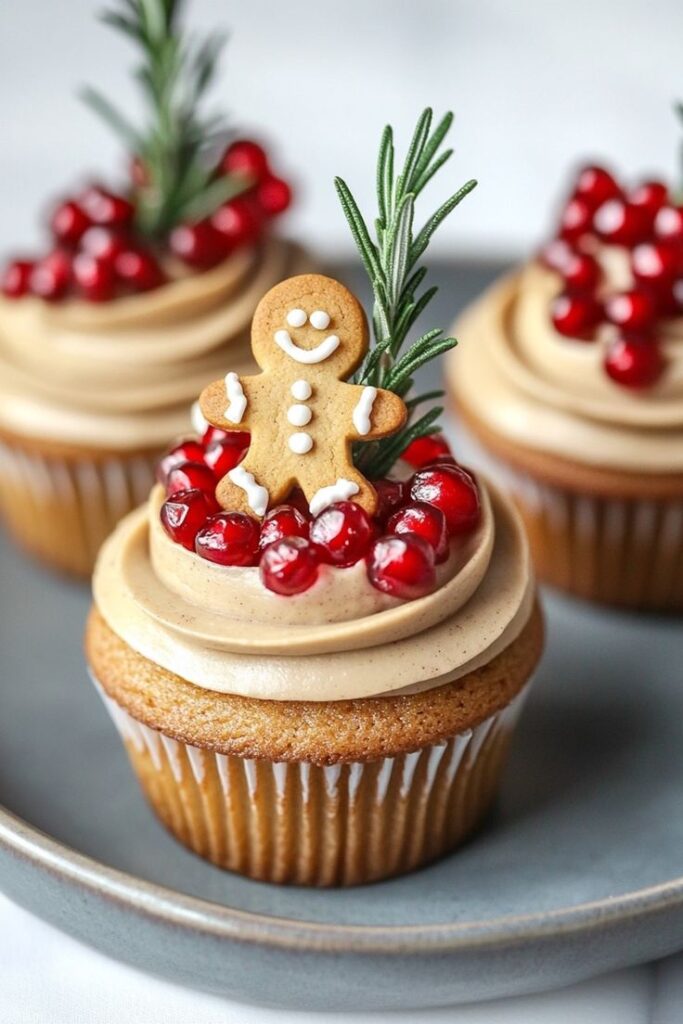 Festive cupcake with gingerbread man, pomegranate seeds, and rosemary on a plate, perfect for the holiday season.