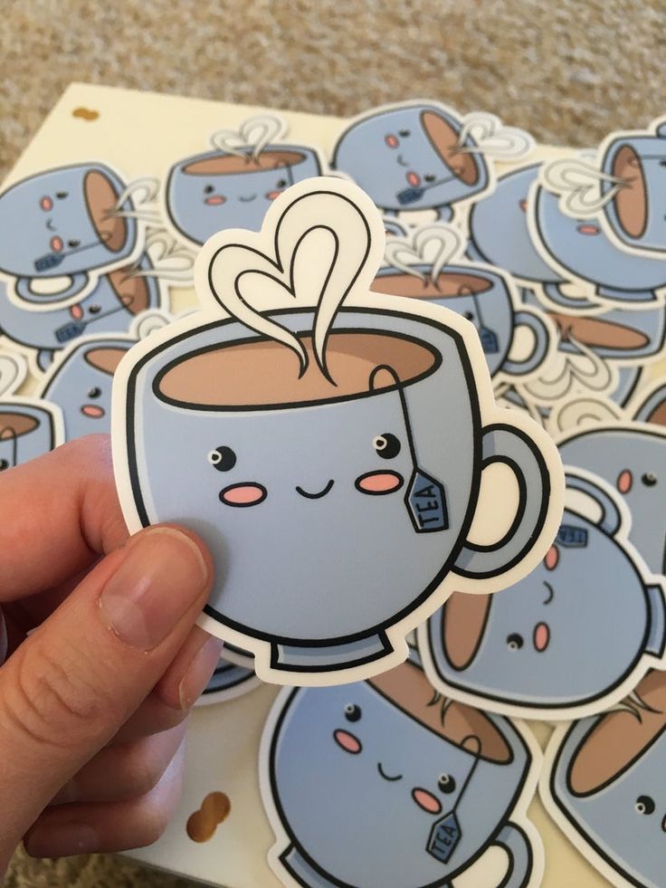 Cute cartoon tea cup stickers with smiling face and heart-shaped steam design, held in hand against similar background.