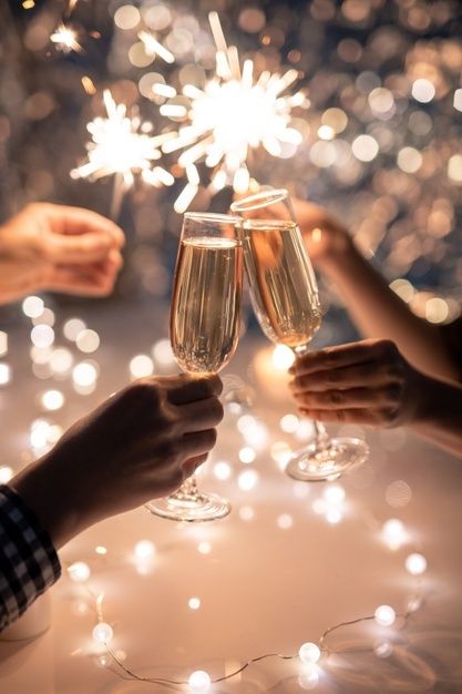 Cheers with champagne flutes amidst sparklers and bokeh lights, celebrating festive moments with elegance and joy.