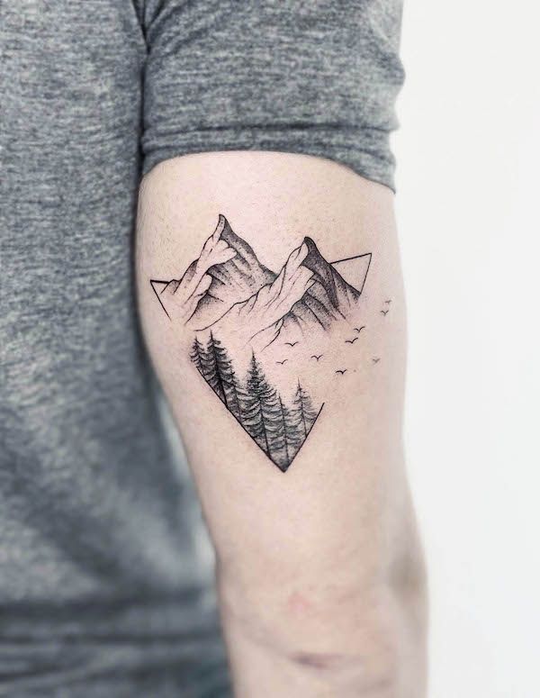 Arm tattoo featuring minimalist mountain scene with trees and birds inside geometric shape.