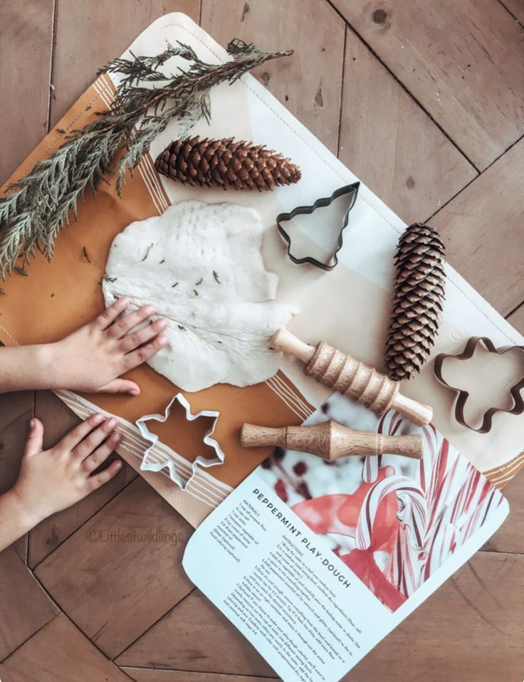 Child playing with peppermint play dough and holiday-themed cookie cutters on a wooden table.