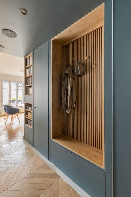 Modern entryway with wood paneling, coat hooks, and built-in shelving in a stylish, minimalist interior design.