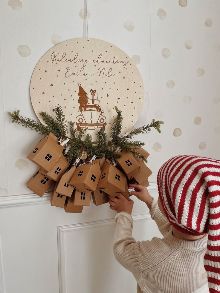 Child interacting with a handmade advent calendar, featuring small house-shaped packages and festive decorations.